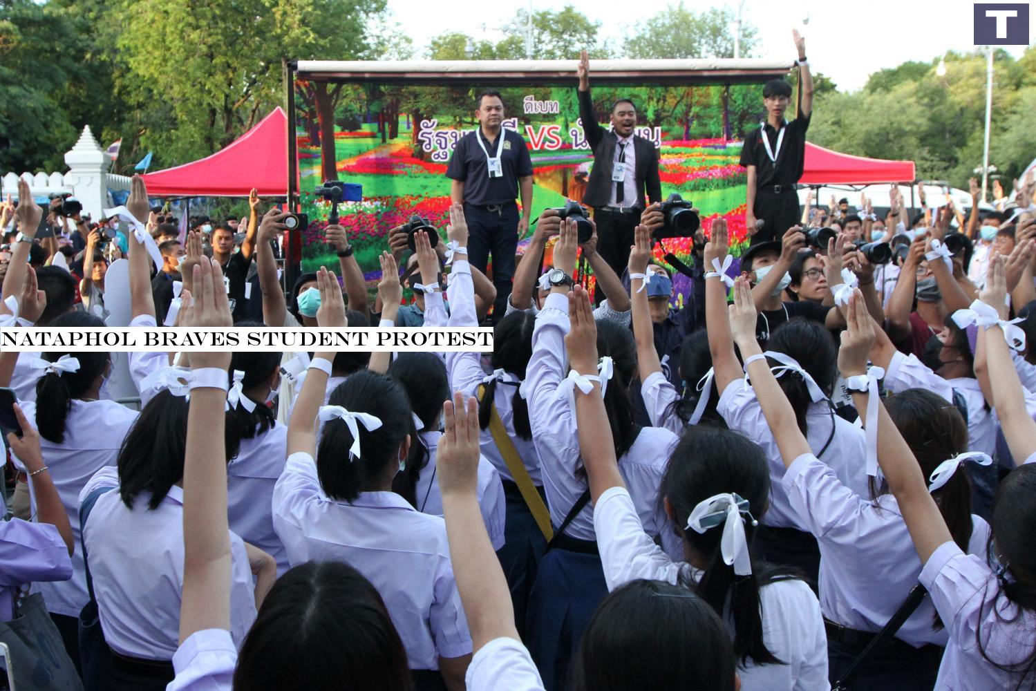 heed our call: Protesting students flash the three-finger salute as Education Minister Nataphol Teepsuwan, far left on stage, listens to their three-point demand at a rally outside the ministry headquarters on Ratchadamnoen Nok Avenue. Nataphol braves student protest