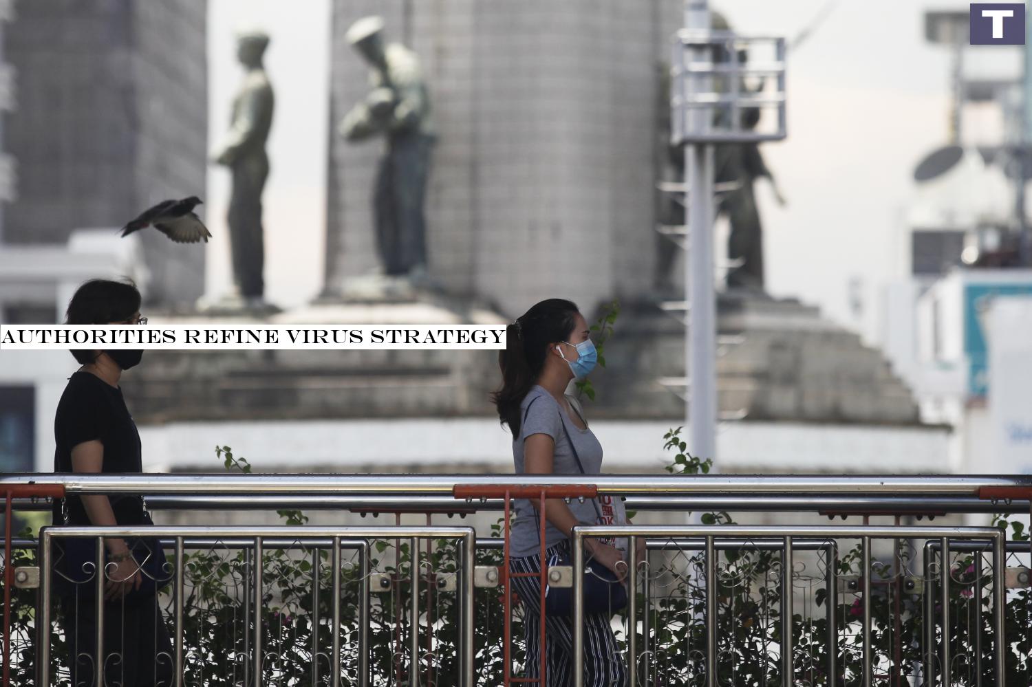 Safety first: Pedestrians wearing face masks walk along a road near the Victory Monument in Phaya Thai district. Health officials stress that wearing face masks should be the norm for people going outdoors. Authorities refine virus strategy