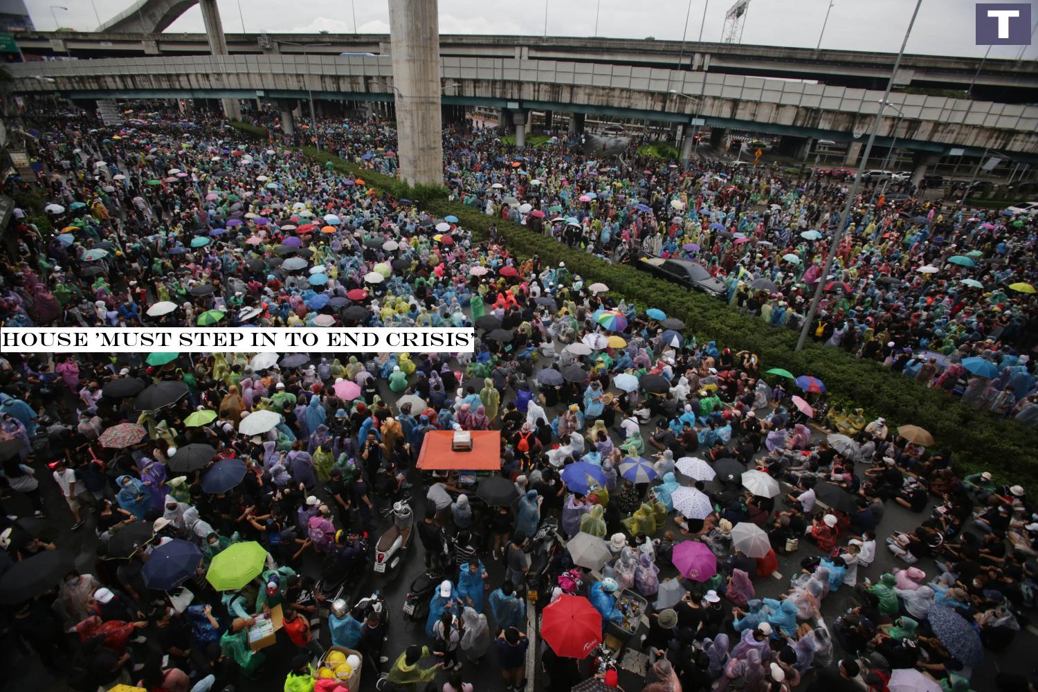 STORM BREWING: Protesters open their umbrellas or wear plastic rain coats to protect them from the rain as they converge at the Lat Phrao intersection. It was one of several protest sites in Bangkok with a heavy turnout on Saturday. House 'must step in to end crisis'